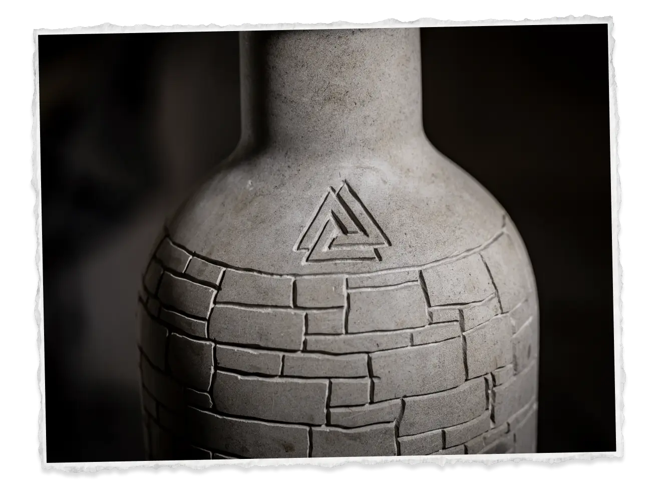 Stone bottle carved with the Piedreros mark, lit from the side